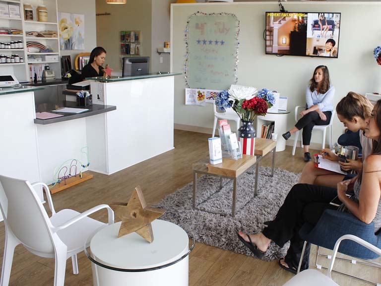 Friendly receptionist helping patient at frontdesk of Encinitas Auto Accident Injury Center in Encinitas